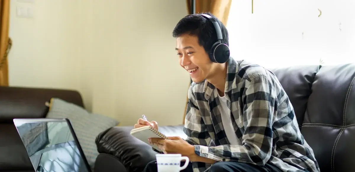 Student taking notes while attending to an online class