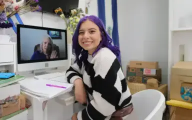 Student wearing a stripped sweater attending to an online class